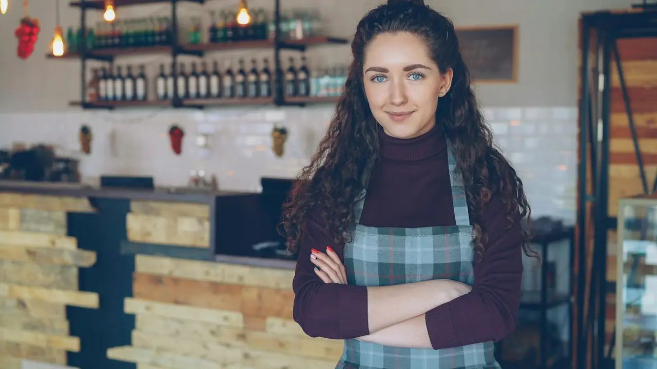 A smiling small-business owner standing in her coffee shop
